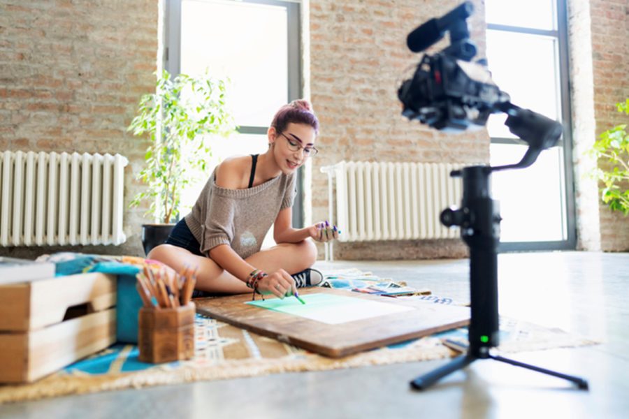 Photo of woman sitting on floor in front of her camera conducting a DIY live stream from her home. Learn how to live stream with Tampa's leading digital marketing agency: Bake More Pies.